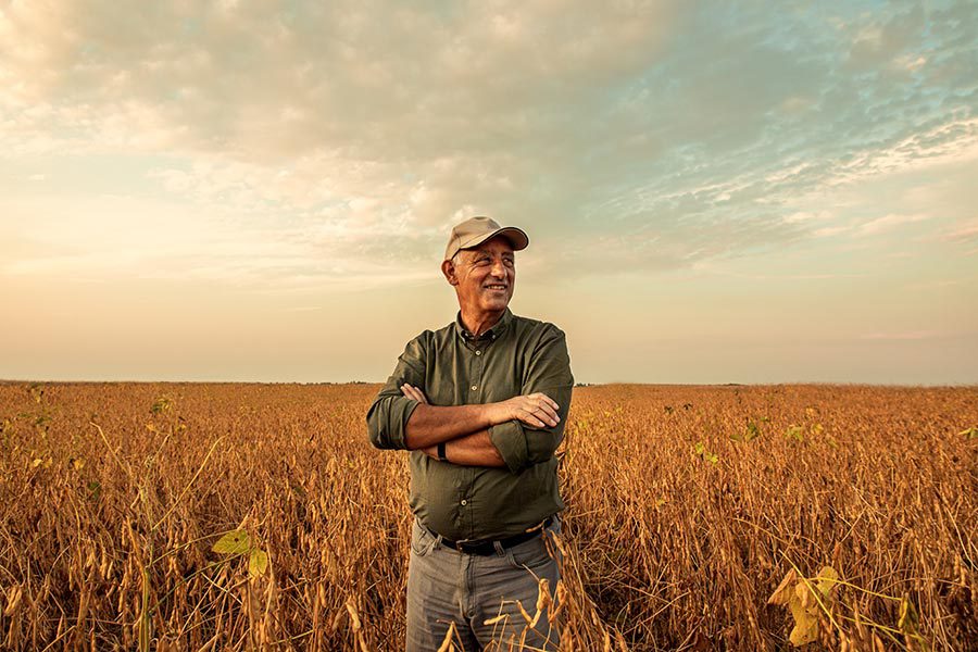 Specialized Business Insurance - Farmer Stands in His Field, Arms Crossed, Smiling